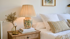 Cozy bedroom styling featuring a rustic wooden nightstand with a vintage floral lamp and books.