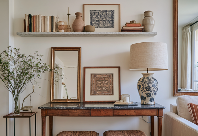 Console table styling featuring antique wood, framed art, and a patterned ceramic table lamp in a living room.