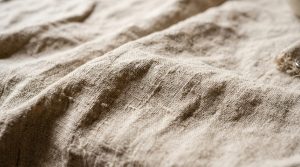 Close-up view of heavy raw linen fabric showing natural texture and woven slubs for linen fabric care.