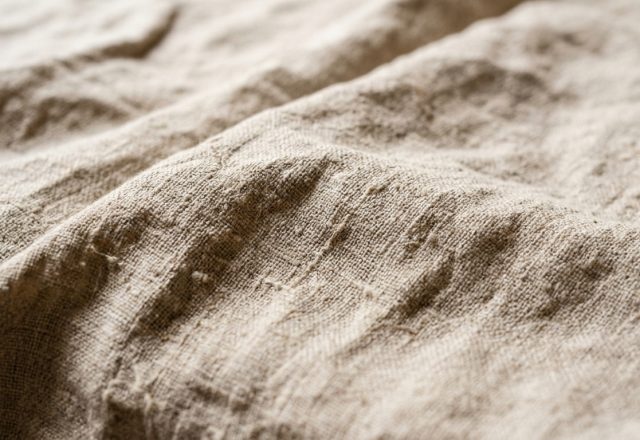Close-up view of heavy raw linen fabric showing natural texture and woven slubs for linen fabric care.