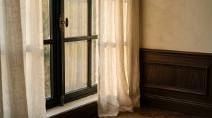 Natural light interior design featuring sheer linen curtains and dark wood wainscoting.