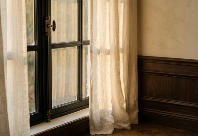 Natural light interior design featuring sheer linen curtains and dark wood wainscoting.