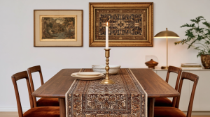 Midcentury modern dining room table styled with a patterned runner, brass candlestick, and velvet chairs.