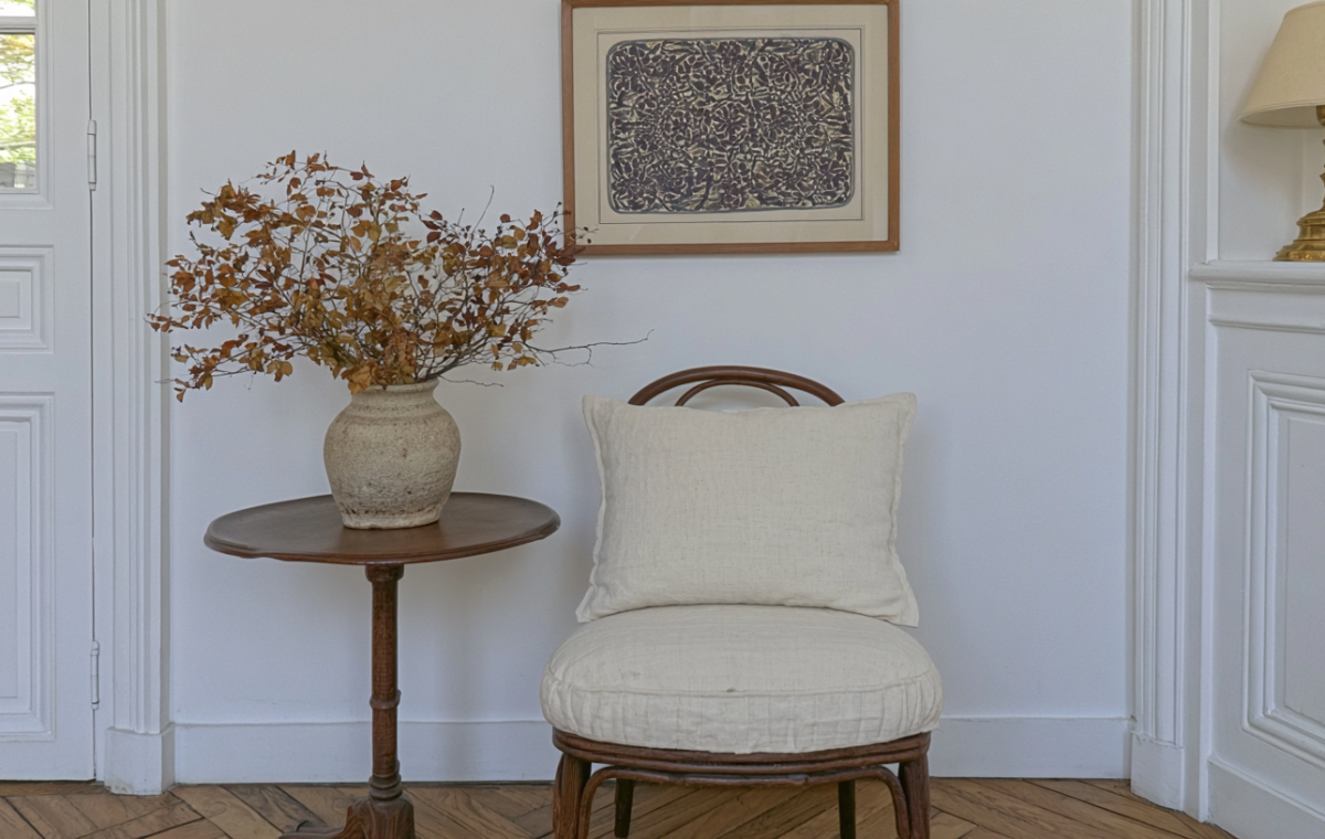 Neutral corner styling featuring an antique wooden table, dried botanicals, and a linen accent chair.