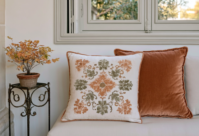 Neutral living room pillows featuring a patterned square cushion and a solid rust velvet throw pillow on a white sofa.