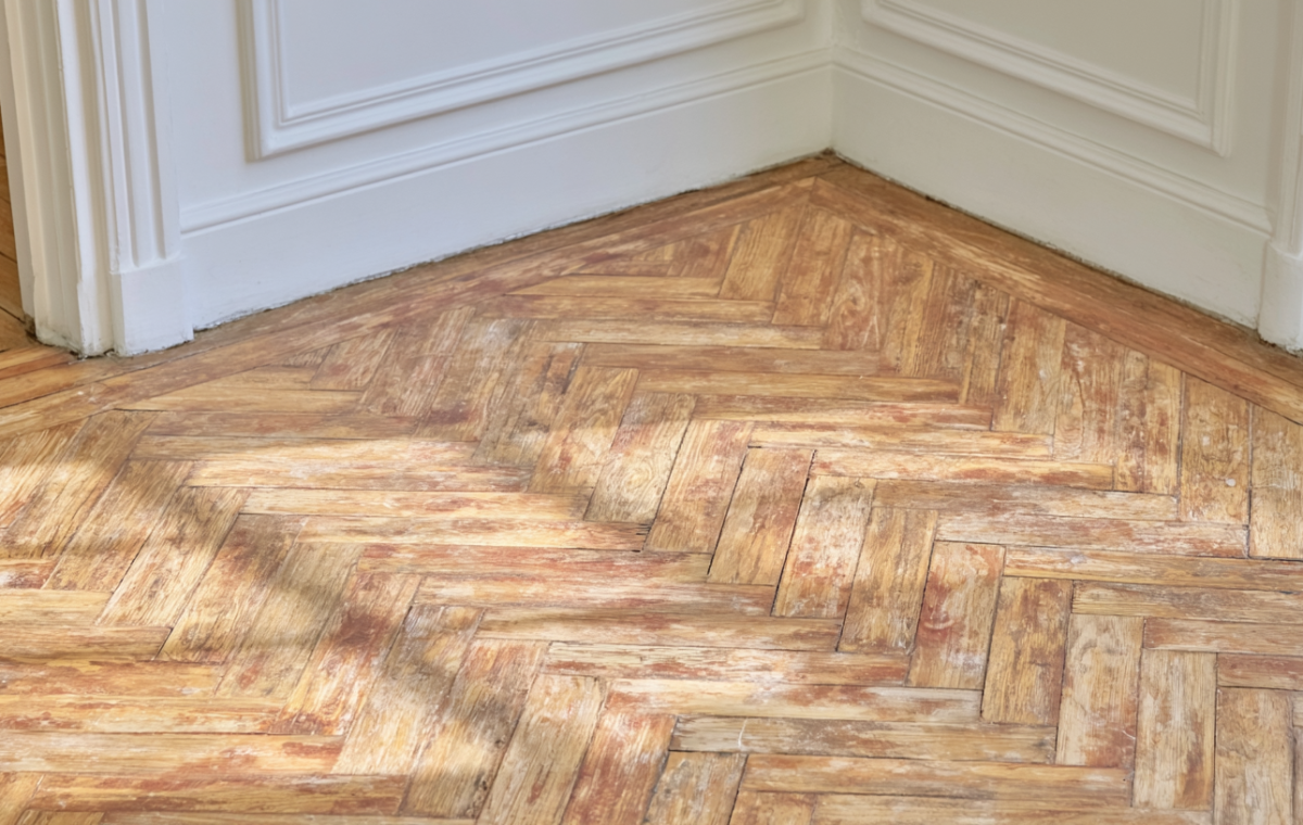 Close up of worn herringbone parquet floor needing restoration in a historic room