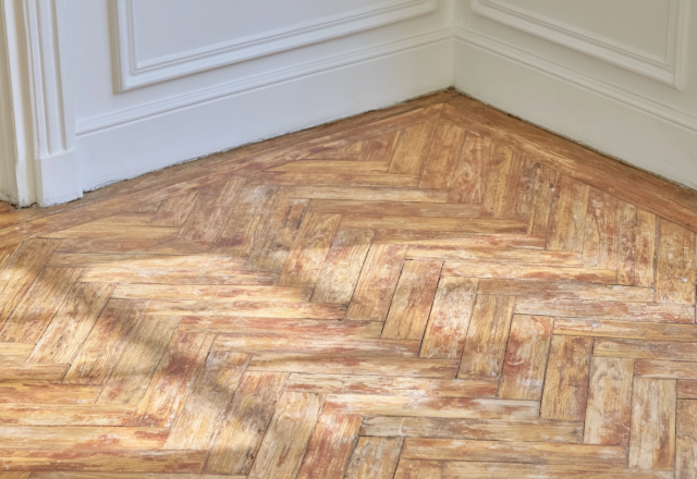 Close up of worn herringbone parquet floor needing restoration in a historic room