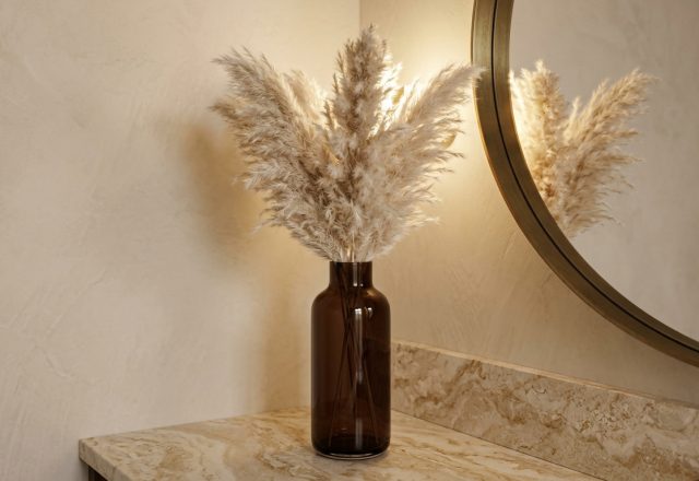 Powder room decor ideas featuring pampas grass in an amber glass vase on a marble vanity