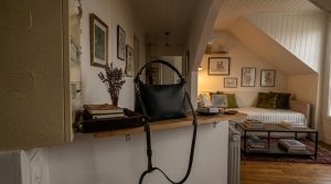 Stylish entryway drop zone featuring a black leather handbag on a wooden ledge with a catch-all tray and dried flowers.