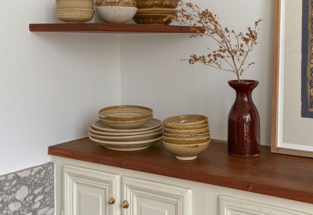 Open shelving kitchen organization featuring stacked ceramic plates and earth-toned pottery.