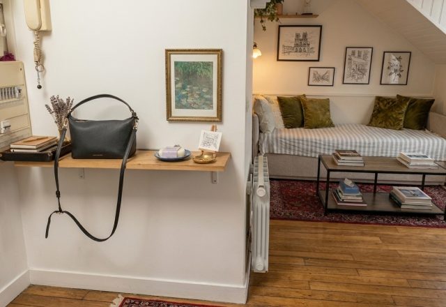 A clean small entryway drop zone featuring a floating wooden shelf and a black leather handbag.