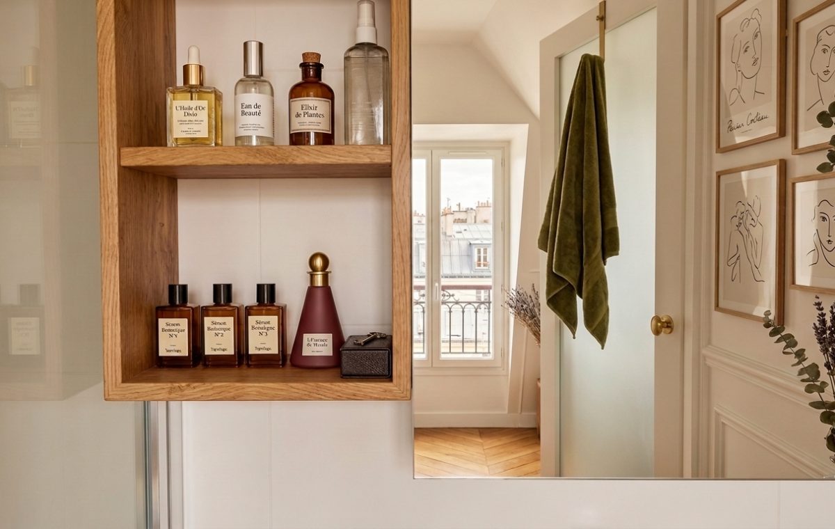 Close up of wooden bathroom floating shelves styled with glass skincare bottles and minimalist decor.