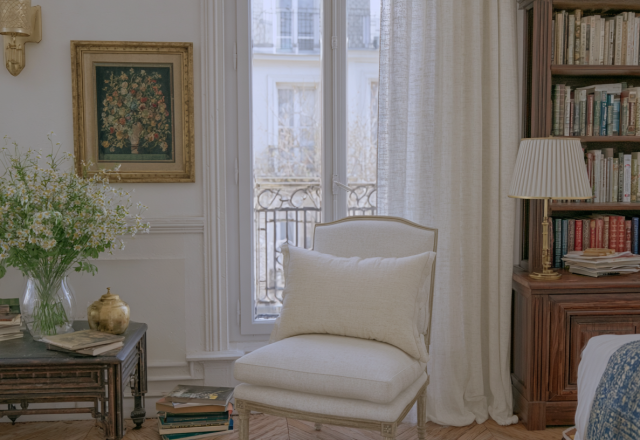 Cozy reading room interior design featuring built-in bookshelves, a white linen chair, and a large window.