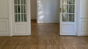 Parquetry wood floors inside a historic room with white double doors.