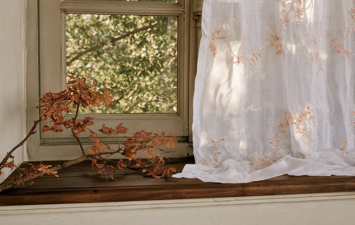 Rustic window sill decor featuring a foraged autumn branch and a sheer embroidered white curtain.