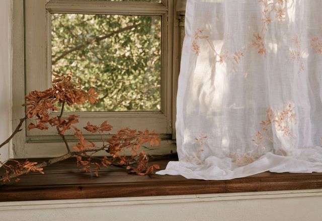 Rustic window sill decor featuring a foraged autumn branch and a sheer embroidered white curtain.