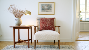 Scandinavian armchair styling featuring a white boucle chair, wooden side table, and brass lamp in a bright room.