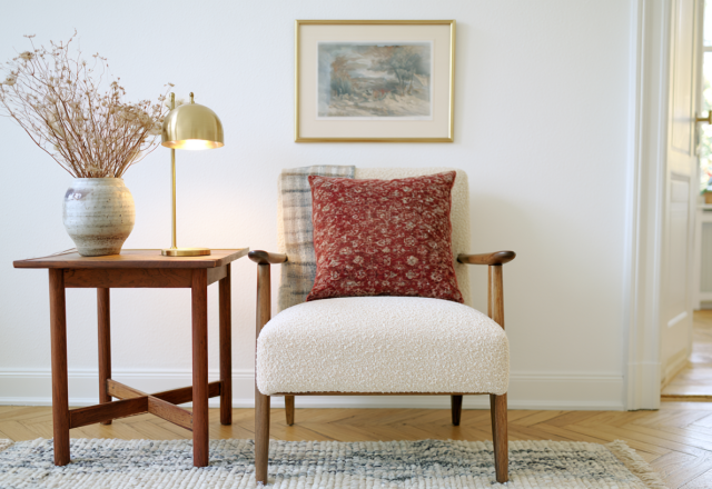 Scandinavian armchair styling featuring a white boucle chair, wooden side table, and brass lamp in a bright room.