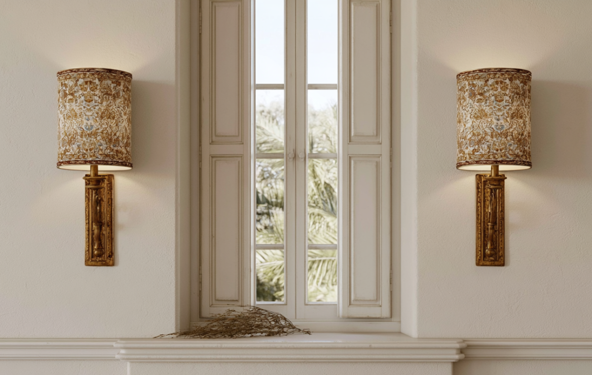 A pair of patterned fabric shade wall sconces mounted on either side of a historic shuttered window using sconce lighting ideas.