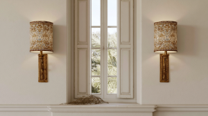 A pair of patterned fabric shade wall sconces mounted on either side of a historic shuttered window using sconce lighting ideas.