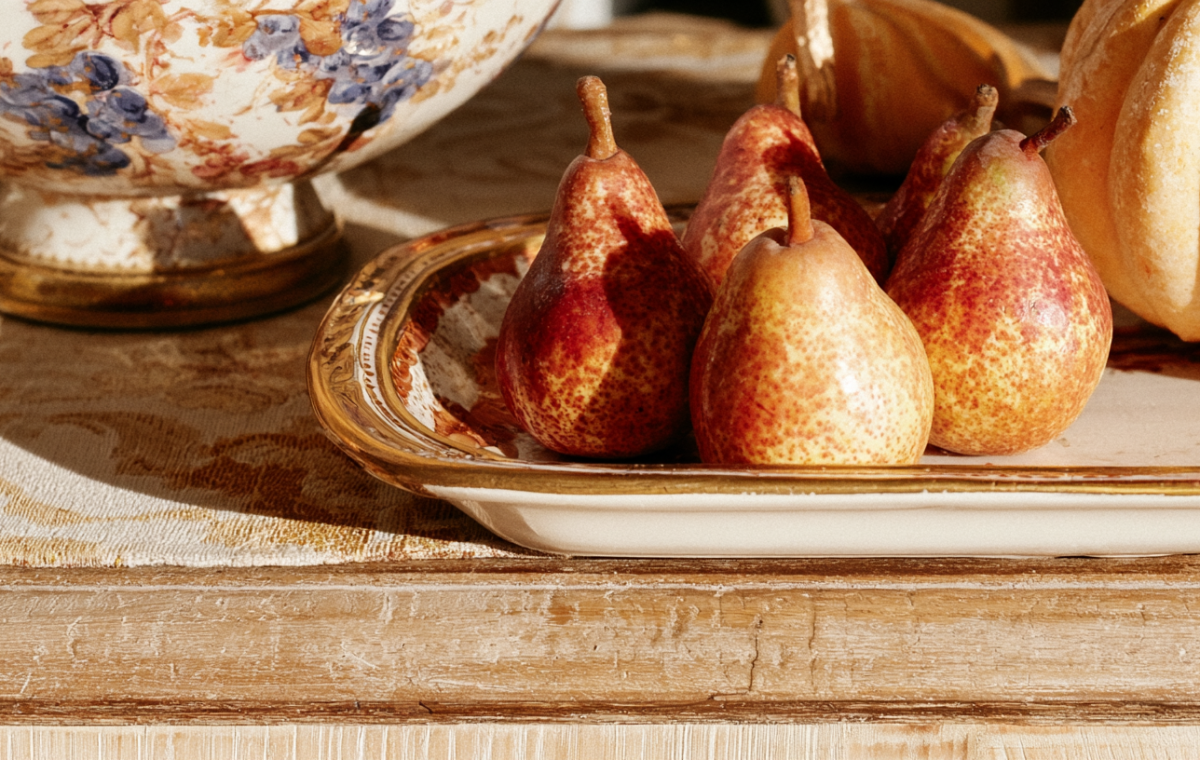 Seasonal tabletop styling featuring fresh pears and vintage ceramics on a rustic wooden console table