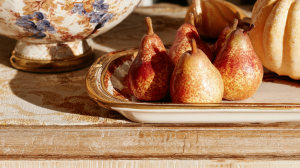 Seasonal tabletop styling featuring fresh pears and vintage ceramics on a rustic wooden console table