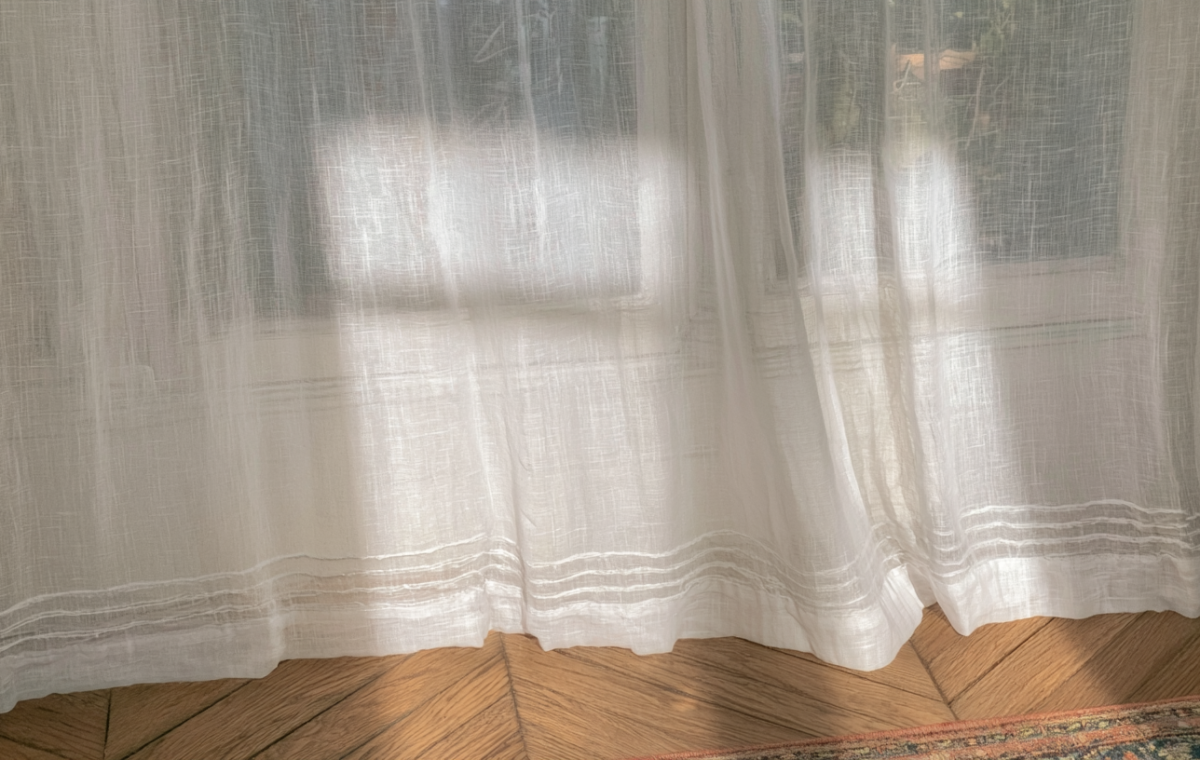 Lightweight sheer linen curtains gently filtering morning sunlight onto hardwood herringbone floors