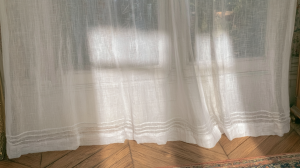 Lightweight sheer linen curtains gently filtering morning sunlight onto hardwood herringbone floors