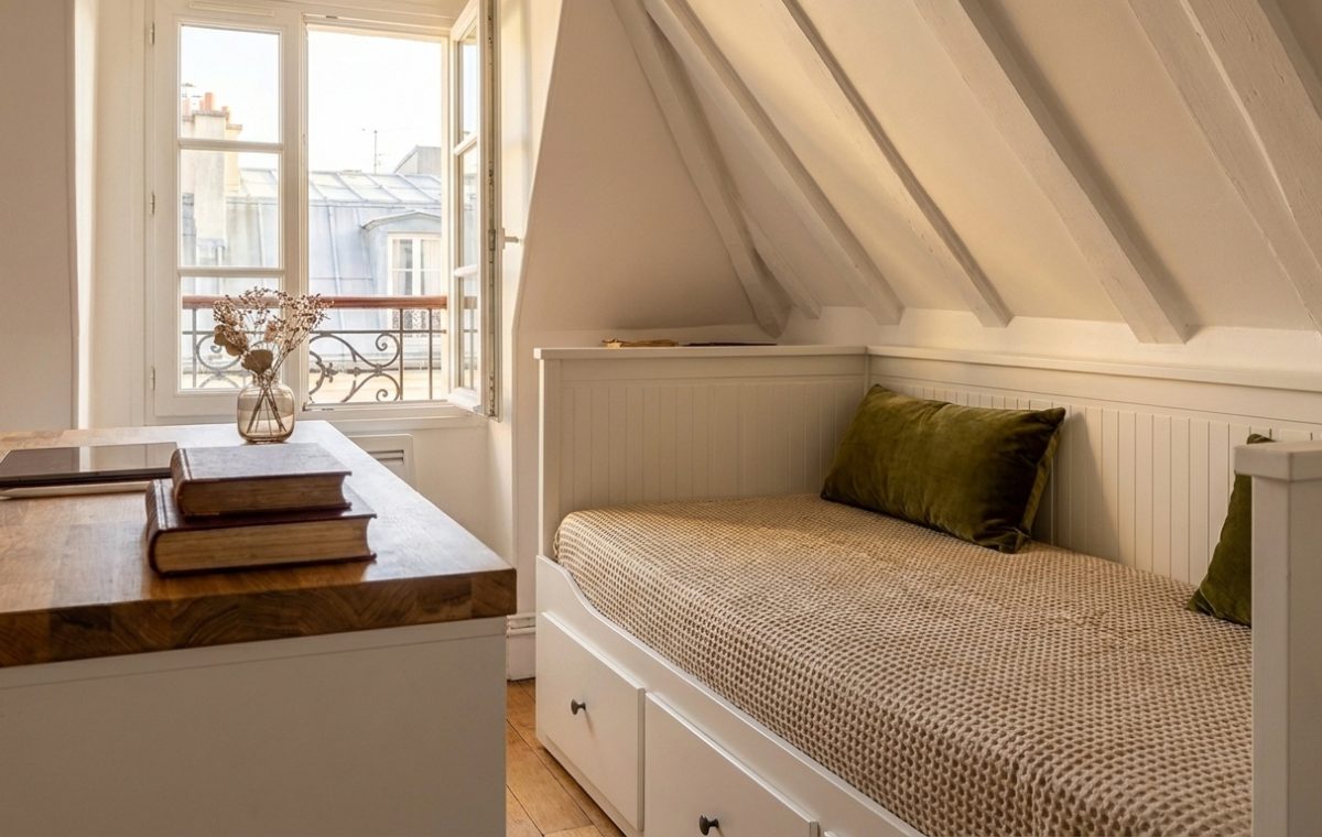 Cozy attic bedroom layout featuring a white built-in daybed under sloped ceilings and a wooden desk near a sunny window
