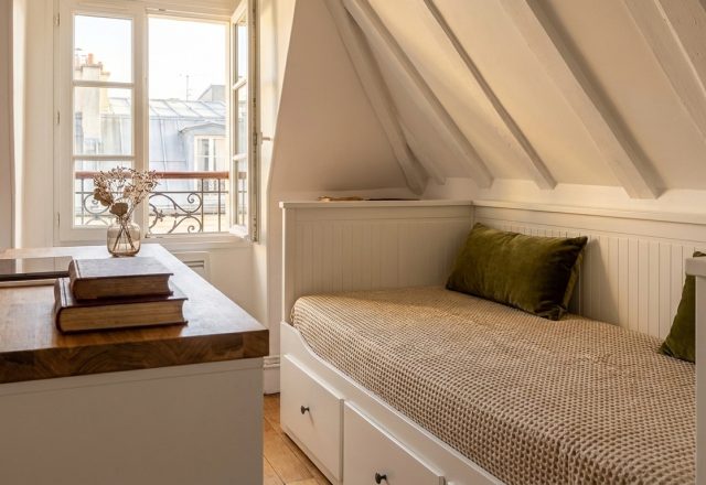 Cozy attic bedroom layout featuring a white built-in daybed under sloped ceilings and a wooden desk near a sunny window