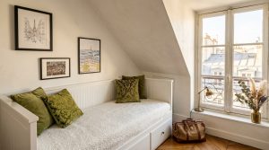 Cozy attic guest bedroom with white daybed, sloped ceilings, and green velvet pillows