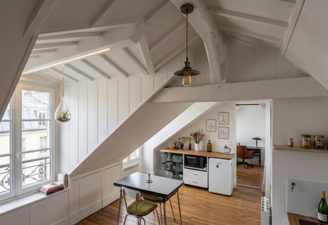 Bright attic kitchen layout featuring sloped white paneled ceilings and compact wooden flooring.