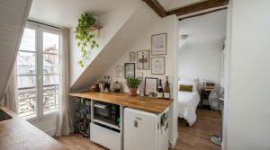 A clever small attic kitchen layout featuring a wooden countertop, under-counter fridge, and slanted white walls.