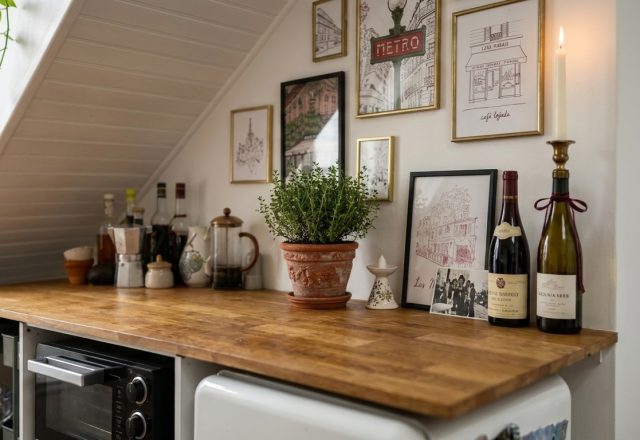 A cozy small kitchen layout featuring wooden countertops, framed wall art, and an under-counter microwave in an attic space.