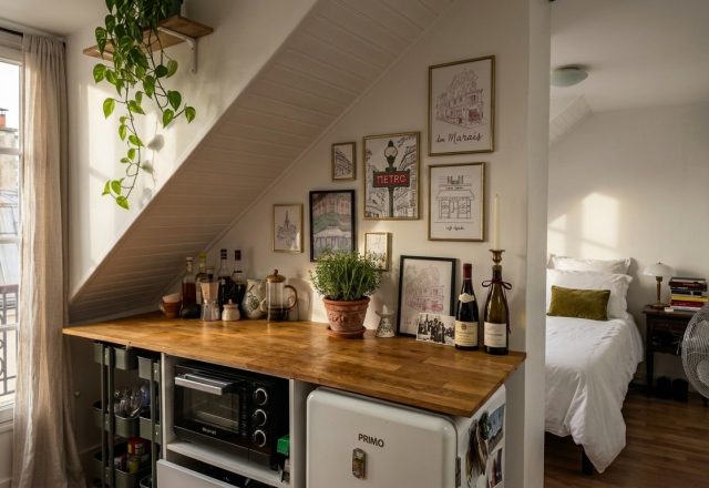 A clever small kitchenette layout featuring a wooden countertop, mini fridge, and toaster oven tucked beneath a sloped attic ceiling.
