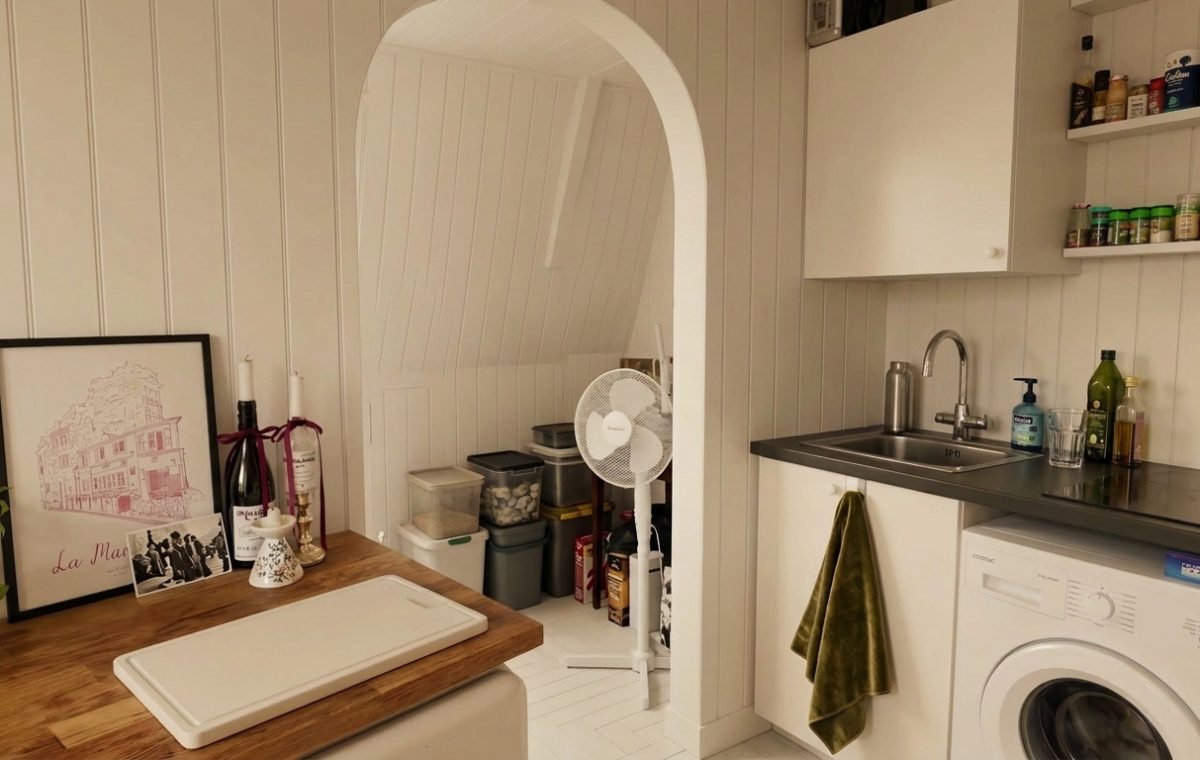 Bright small utility room design featuring white panel walls, compact laundry appliances, and open shelving.