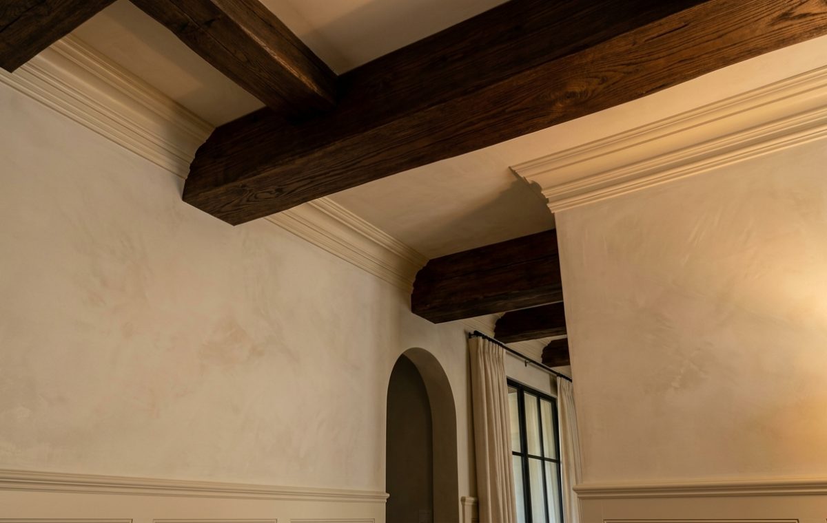 Dark wood ceiling beams contrasted against textured plaster walls in a transitional style living room.