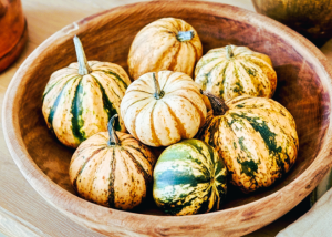 Wooden bowl filled with assorted mini pumpkins and striped gourds for fall bowl centerpieces
