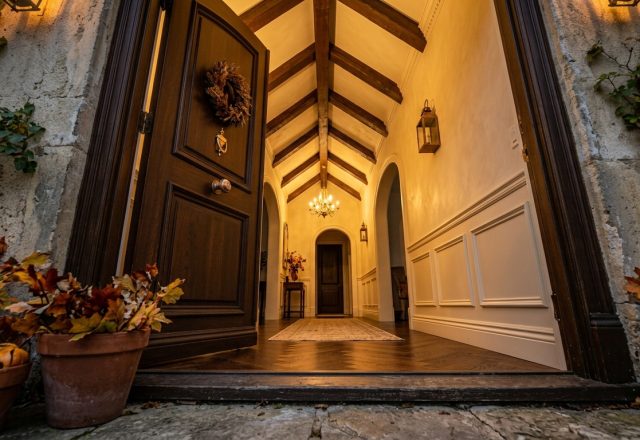Warmly lit front entryway design featuring dark wood double doors and exposed wooden beams.