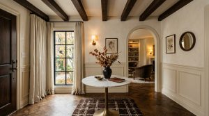 Elegant front entryway interior design featuring herringbone floors, an arched hallway, and a round marble table.