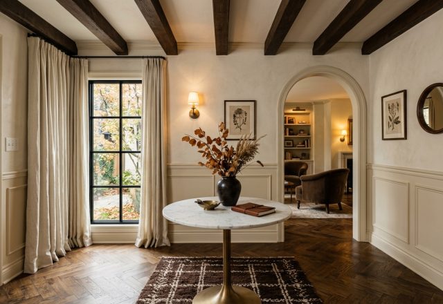 Elegant front entryway interior design featuring herringbone floors, an arched hallway, and a round marble table.