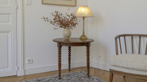 Vintage wooden accent table with a brass lamp and dried florals in a bright room.