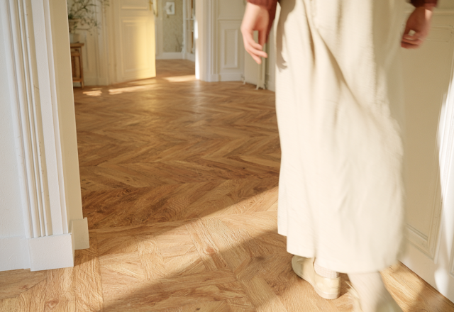 Sunlight illuminating a classic parquet flooring pattern in a bright hallway interior.