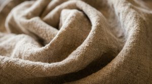 Close-up shot of tumbled neutral linen fabric showing rich texture and organic folds.