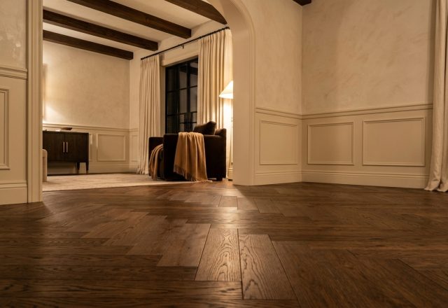Close up of herringbone wood flooring in a luxury transitional living room with wainscoting.