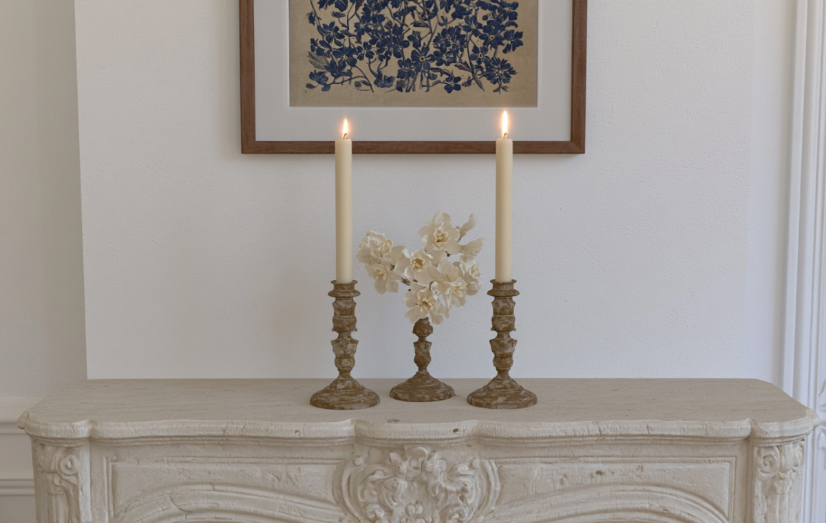 Elegant mantel decor ideas featuring lit taper candles and white flowers on a vintage stone fireplace