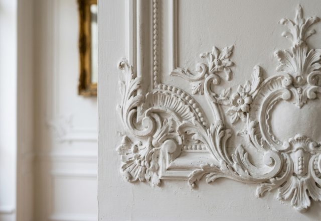 Close up of an intricate plaster wall molding design with floral relief details in a historic home.