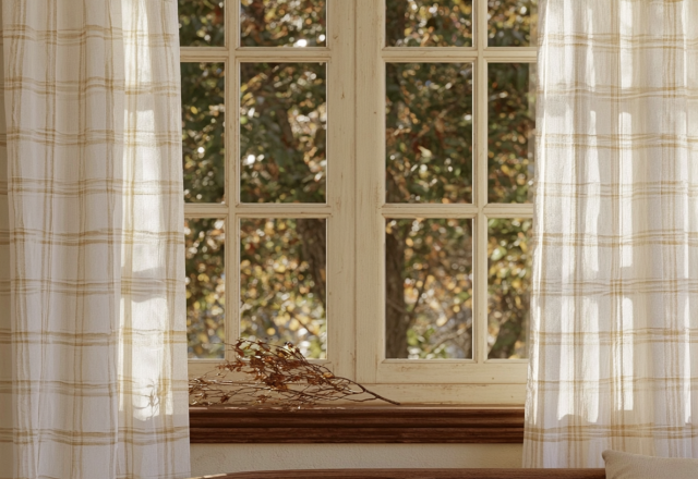 Natural window treatments featuring light plaid linen curtains framing a multi-pane rustic window.