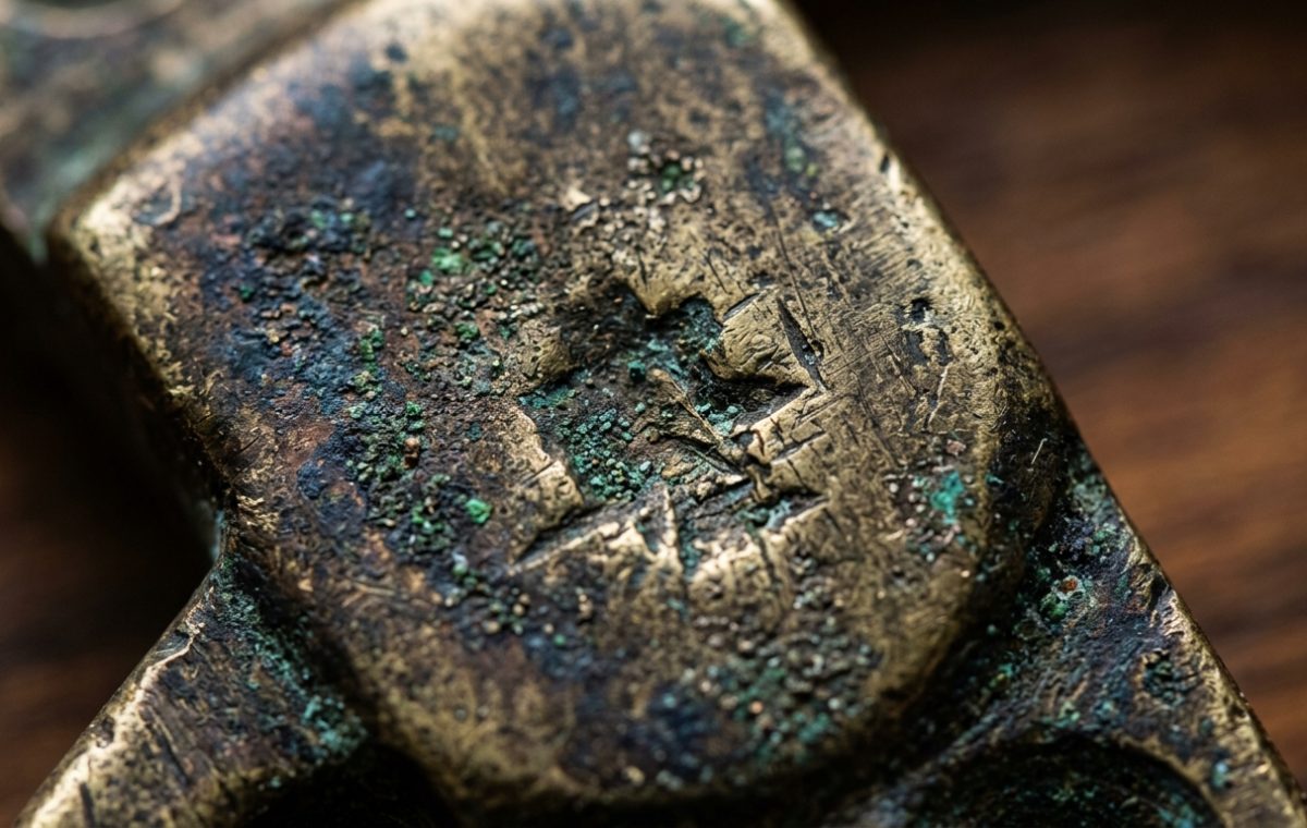 Close up of an antique brass patina with green verdigris oxidation on vintage metal hardware.