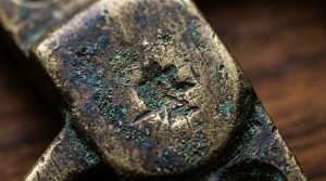 Close up of an antique brass patina with green verdigris oxidation on vintage metal hardware.